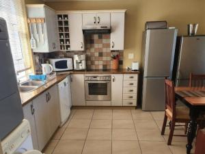 eine Küche mit Geräten aus Edelstahl und einem Tisch darin in der Unterkunft Pinnacle Point Golf Estate - Golf Villa 10-1 in Mossel Bay