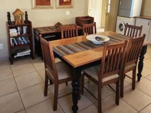 ein Holztisch mit Stühlen und einem Teller darauf in der Unterkunft Pinnacle Point Golf Estate - Golf Villa 10-1 in Mossel Bay + 7 Fotos