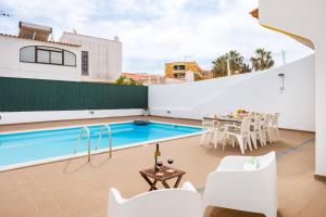 a patio with a table and chairs and a swimming pool at Villa Nobre by The Portuguese Butler in Albufeira