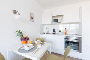 a white kitchen with a table with fruit on it at Pauzo Balaton in Balatonföldvár