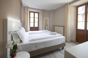 a bedroom with a large bed with white sheets at Hotel Il Portico in Cannobio