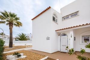 a white house with a palm tree in front of it at Villa Nobre by The Portuguese Butler in Albufeira