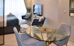 uma sala de estar com uma mesa de vidro e cadeiras em Elegant Studio in park View JVC em Dubai