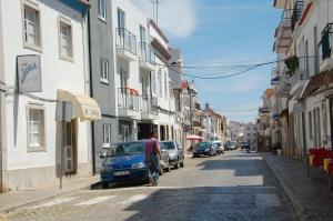 a man walking down a street with a blue car at A Casa da Maria in Tavira