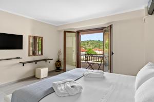 Biała sypialnia z dużym łóżkiem i balkonem w obiekcie The Dandy Villas Sivota w mieście Sivota