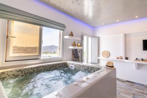 a jacuzzi tub in a room with a window at Sunset Faros in Akrotiri