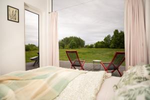 a bedroom with a bed and two chairs on a porch at Pilwa 17 - Domek in Pilwa +26 photos