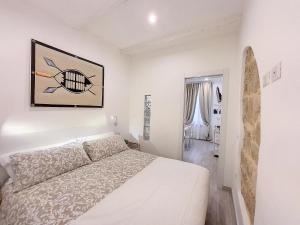 a white bedroom with a bed and a surfboard at Protea House in Alghero