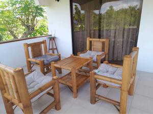 un porche con 4 sillas y una mesa y sillas de madera en Beth's Villa en Moalboal