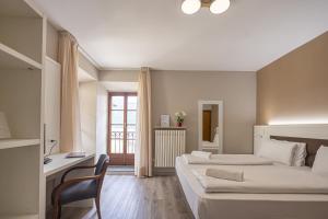 sypialnia z 2 łóżkami, biurkiem i krzesłem w obiekcie Hotel Il Portico w mieście Cannobio