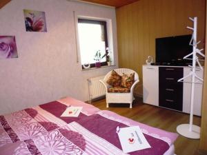 1 dormitorio con 1 cama, TV y silla en Ferienwohnung am Wald, en Unterlüß