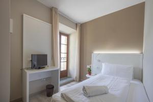 Schlafzimmer mit einem weißen Bett und einem TV in der Unterkunft Hotel Il Portico in Cannobio