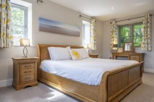 a bedroom with a large wooden bed and two windows at The Goosebec in Burnham Market