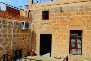a brick building with a door and a balcony at Mons Masius Boutique Hotel Cafe in Midyat