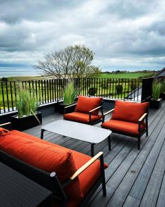 a deck with two couches and a table and chairs at 17 The Fairways in Broadstairs