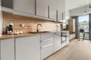 Una cocina con gabinetes blancos y un fregadero. en Apartament Lynx HANZA POOL SAUNA, en Szczecin