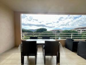 ein Esszimmer mit einem Tisch und Stühlen sowie einem großen Fenster in der Unterkunft Appartement Résidence Salin Bay in Porto-Vecchio