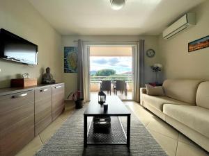 ein Wohnzimmer mit einem Sofa und einem Tisch in der Unterkunft Appartement Résidence Salin Bay in Porto-Vecchio
