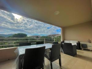 einen Balkon mit einem Tisch und Stühlen sowie einem großen Fenster in der Unterkunft Appartement Résidence Salin Bay in Porto-Vecchio