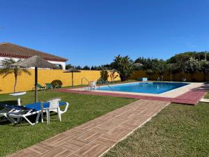 a swimming pool in a yard with chairs and a table at Hostal Los Rosales in Conil de la Frontera