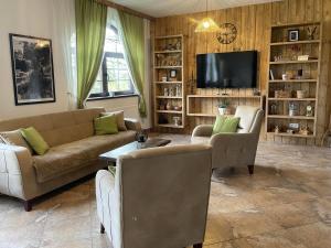 a living room with a couch and chairs and a tv at Casa meșterului in Sohodol