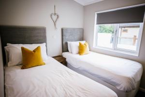 2 camas con almohadas amarillas en una habitación con ventana en Ream Hills Holiday Park en Blackpool
