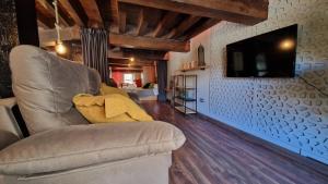 ein Wohnzimmer mit einem Sofa und einem Fernseher an der Wand in der Unterkunft LOFT LA CATEDRAL DE CASA BOTES in Cuenca