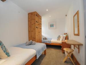 a bedroom with two beds and a wooden cabinet at Mill House in Lostwithiel