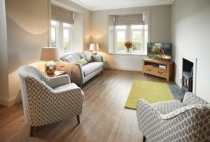 ein Wohnzimmer mit einem Sofa, Stühlen und einem TV in der Unterkunft Netherwood Lodge in Dumfries