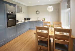 a kitchen with blue cabinets and a table and chairs at Netherwood Lodge in Dumfries