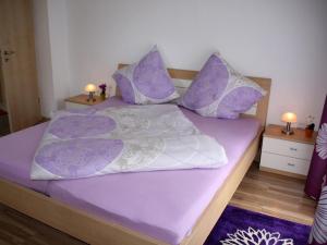 ein Bett mit lila und weißen Laken und Kissen in der Unterkunft Dogge, Ferienwohnung in Celle
