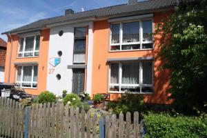 ein orangefarbenes und weißes Haus hinter einem Zaun in der Unterkunft Dogge, Ferienwohnung in Celle