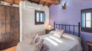 sypialnia z fioletowymi ścianami i łóżkiem z kapciami w obiekcie Villa Azul de Frigiliana by Ruralidays w mieście Frigiliana