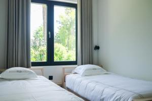 2 camas en una habitación con ventana en Gasthuis Veurne en Veurne