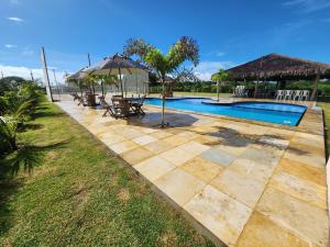 a swimming pool with chairs and an umbrella at Cabanas da Sorte in Fortim