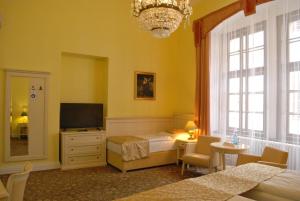 a bedroom with a bed and a television and a chandelier at Hotel Metamorphis in Prague