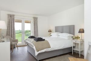 a white bedroom with a large bed and a window at Strawberry Lodge 