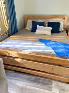 a wooden bed with blue pillows in a bedroom at Kivulini House - close to the beach in Dar es Salaam