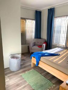 a bedroom with a bed and a couch and a chair at Kivulini House - close to the beach in Dar es Salaam