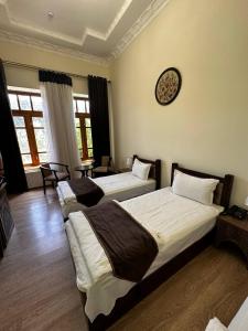 1 dormitorio con 2 camas y reloj en la pared en Imperial Palace, en Bukhara