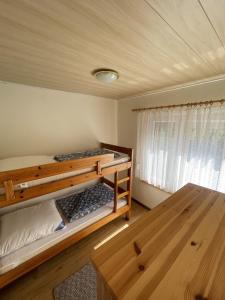 1 Schlafzimmer mit 2 Etagenbetten und einem Holztisch in der Unterkunft Gemütlicher Bungalow an der Mecklenburgischen Seenplatte in Jabel