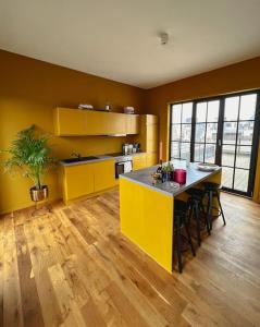 a kitchen with yellow cabinets and a table with stools at Laila Penthouse in Antwerp