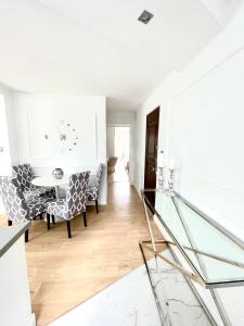 a dining room with a table and chairs and a clock at Smart Apartment Ustronie Morskie in Ustronie Morskie