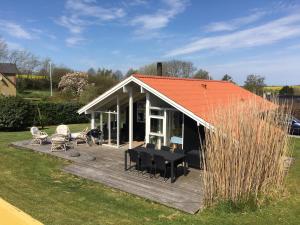 Two-Bedroom Holiday Home for 6 in Vemmingbund في Broager: منزل به سقف برتقالي وسطح خشبي