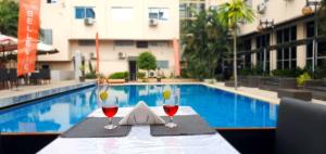 金夏沙的住宿－Hotel Belle Vie，游泳池畔的桌子上放上两杯酒