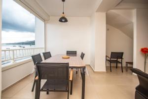 una sala da pranzo con tavolo, sedie e una grande finestra di Les Pénates - Appt vue mer proche plage a Saint-Pierre