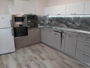 a kitchen with white appliances and wooden floors at Апартамент Deluxe 7 in Saints Constantine and Helena