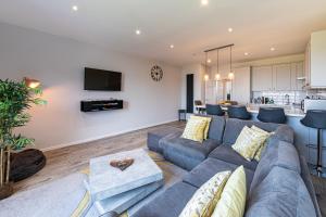Una sala de estar con un sofá azul y una cocina. en 32 Deganwy Beach, en Deganwy