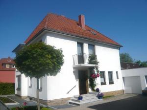 une maison blanche avec un balcon et un arbre dans l'établissement Neumann, Ferienwohnung, à Celle