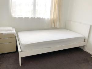 a white bed in a room with a window at Near motorway and supermarket in Auckland